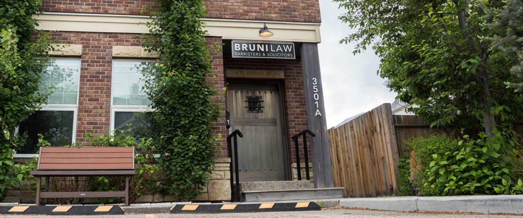 exterior of a heritage brick building with ivy growing up the side and a Bruni law sign above the door