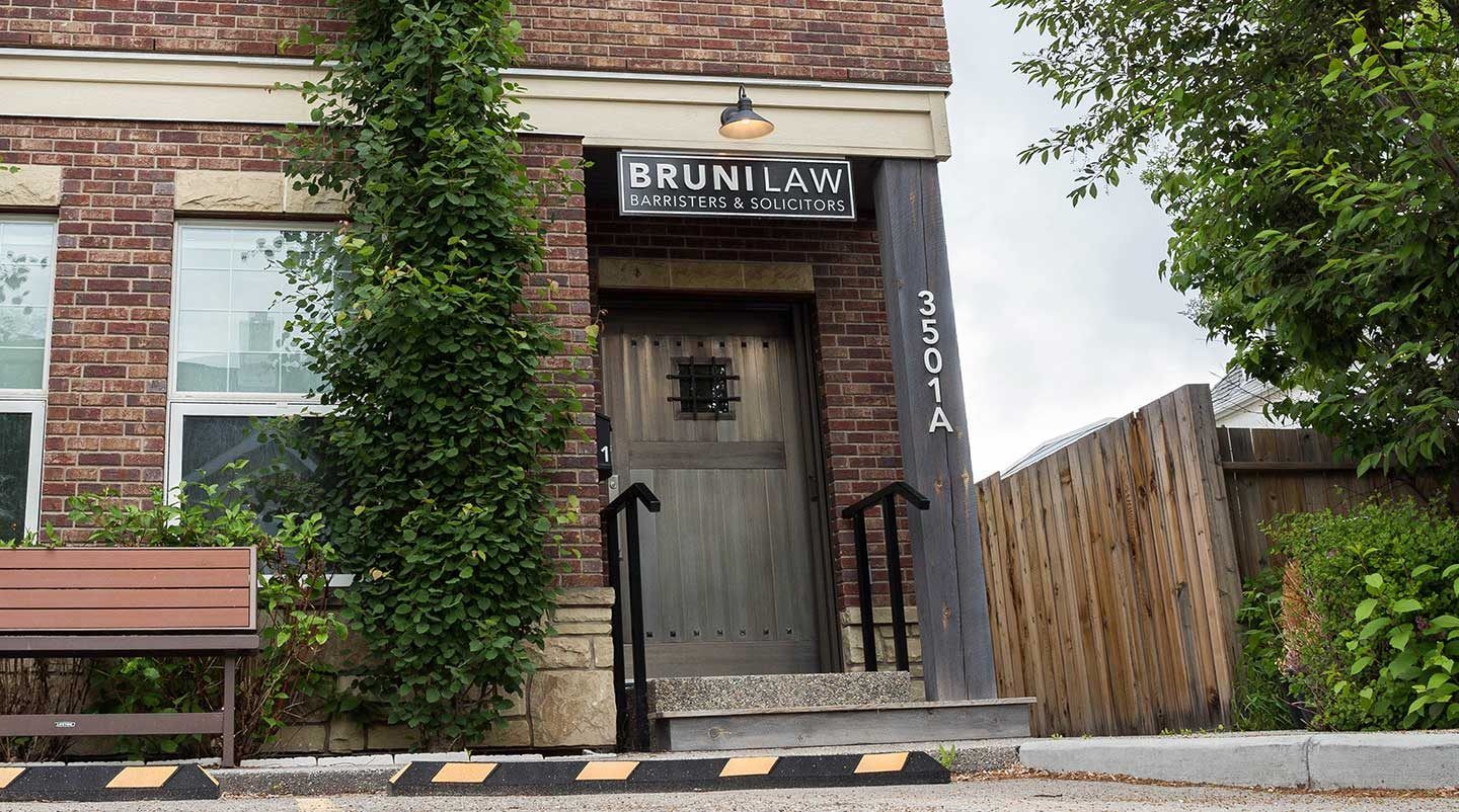 exterior of a heritage brick building with ivy growing up the side and a Bruni law sign above the door