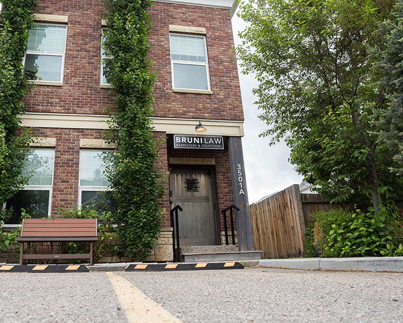 exterior of a heritage brick building with ivy growing up the side and a Bruni law sign above the door